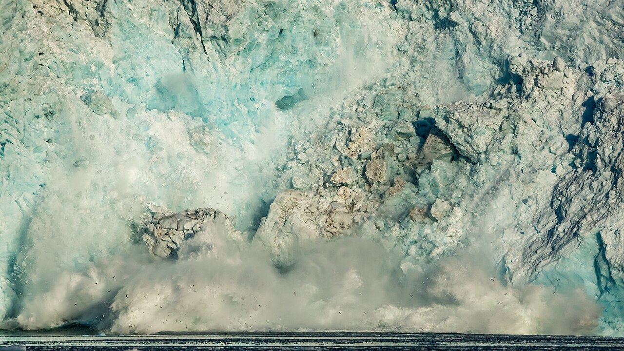 A tidewater glacier calving into the sea in Svalbard, ice breaking apart as the pack ice season shifts